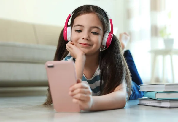 Χαριτωμένο Κοριτσάκι Ακουστικά Και Smartphone Ακούγοντας Audiobook Στο Σπίτι — Φωτογραφία Αρχείου