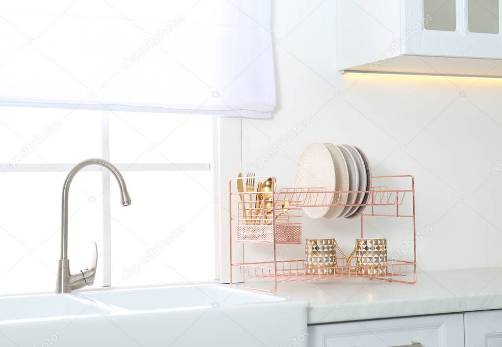 Clean dishes on drying rack in modern kitchen interior