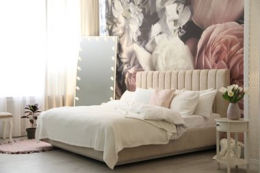 Büyük yataklı, aynalı ve çiçek desenli güzel bir oda.