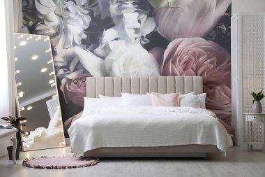 Büyük yataklı, aynalı ve çiçek desenli güzel bir oda.