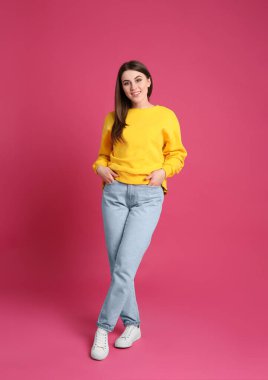 Pembe arka planda genç bir kadının tam boy portresi