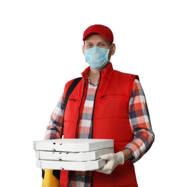 Koruyucu maskeli bir kurye ve arka planda pizza kutuları tutan eldivenler. Coronavirus karantinası sırasında yiyecek teslimatı