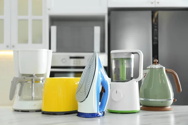 Set of modern home appliances on white marble table in kitchen