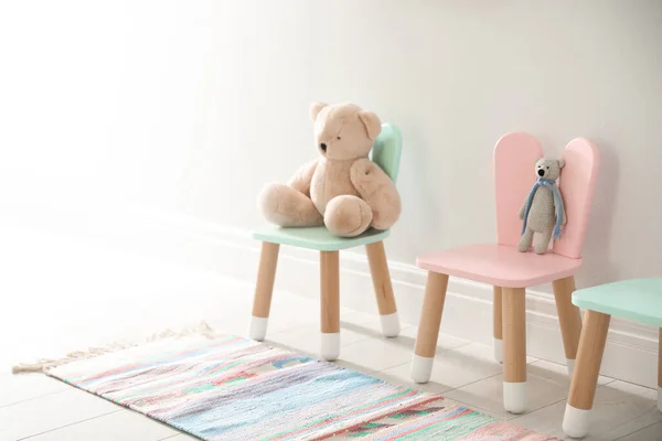 在室内白墙附近的有兔子耳朵的椅子上玩可爱的玩具 儿童房 — 图库照片