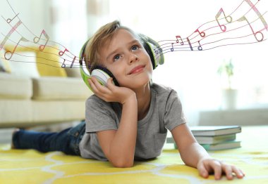 Evde müzik dinleyen kulaklıklı şirin bir çocuk.