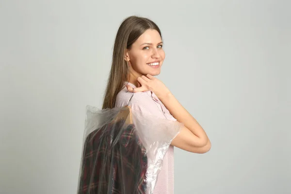 Молодая Женщина Держит Вешалку Рубашкой Пластиковом Пакете Светло Сером Фоне — стоковое фото