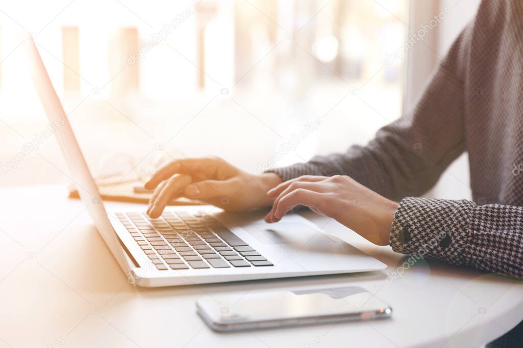 Woman working with laptop at table indoors, closeup