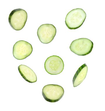 Beyaz arka planda uçan taze salatalık dilimleri.