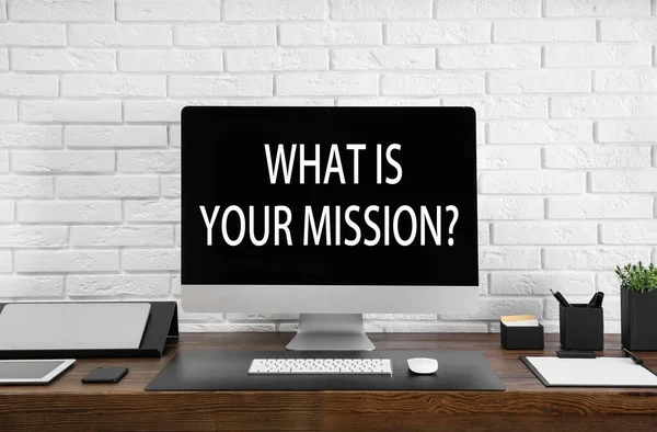 Modern computer with question WHAT IS YOUR MISSION? on screen indoors