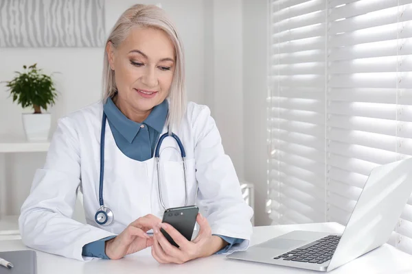 Gammal Kvinnlig Läkare Med Smartphone Vid Bordet Kontoret — Stockfoto