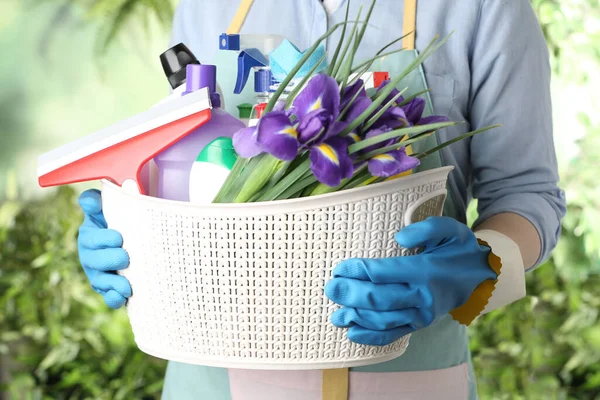 Frau Hält Korb Mit Frühlingsblumen Und Putzutensilien Auf Grün Verschwommenem — Stockfoto