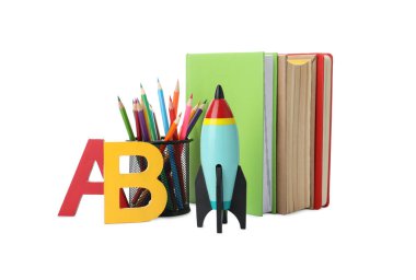 Parlak oyuncak roketi ve beyaz arka planda okul malzemeleri