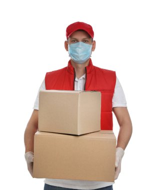 Koruyucu maskeli bir kurye ve beyaz arka planda karton kutular tutan eldivenler. Coronavirus karantinası sırasında teslimat servisi