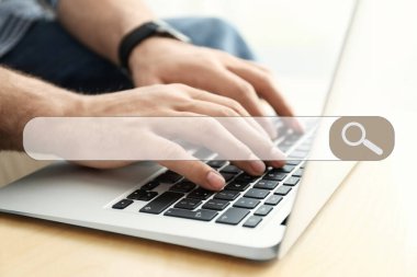 İnternet tarayıcısının arama çubuğu ve masadaki modern dizüstü bilgisayarda çalışan adam, yakın plan