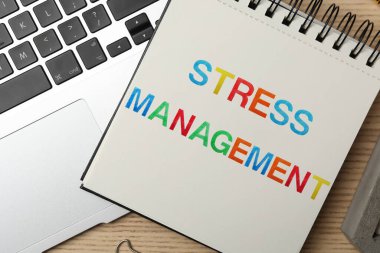 STRESS MANAGEMENT ve dizüstü bilgisayarlı not ahşap masa, düz yatıyordu