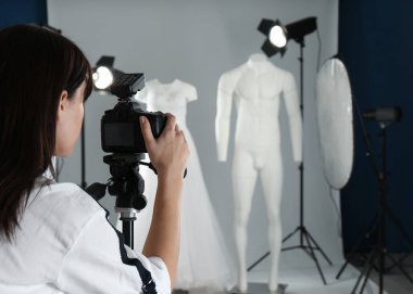 Profesyonel fotoğrafçı fotoğraf stüdyosunda şık giyinmiş hayalet mankenlerin fotoğrafını çekiyor.