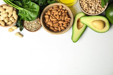 Beyaz arka planda E vitamini bakımından zengin farklı ürünler. Metin için boşluk