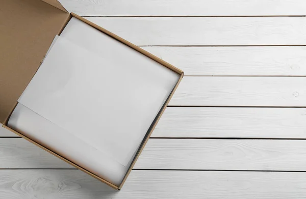 Kartonnen Doos Met Kleding Verpakt Perkament Witte Houten Achtergrond Bovenaanzicht — Stockfoto