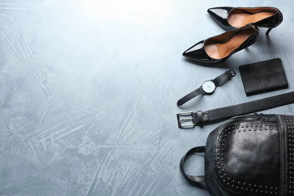 Flat lay composition with leather bag, shoes and accessories on light stone table. Space for text