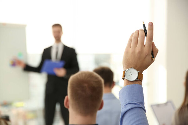 Man raising hand to ask question at business training indoors, closeup