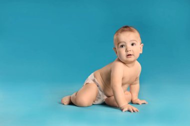 Açık mavi arka planda bebek bezi takmış şirin bir bebek. Metin için boşluk