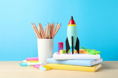 Parlak oyuncak roket ve okul malzemeleri ahşap masada.