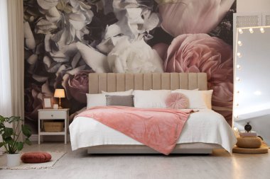 Büyük yataklı, aynalı ve çiçek desenli güzel bir oda.