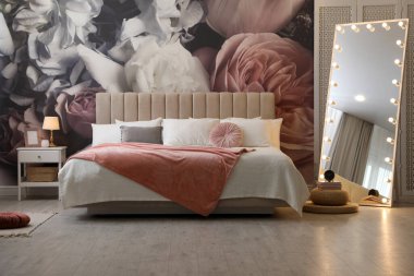 Büyük yataklı, aynalı ve çiçek desenli güzel bir oda.