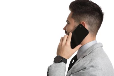 Genç işadamı beyaz arka planda akıllı telefondan konuşuyor.