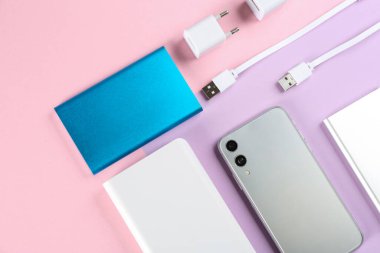Renkli arka planda cep telefonu ve taşınabilir şarj cihazları, düz konum
