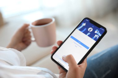 MYKOLAIV, UKRAINE - 16 Mart 2020: Facebook uygulamalı iPhone 11 'i kapalı alanda tutan kadın, yakın plan
