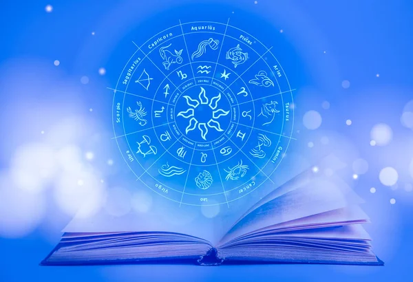 Open book and illustration of zodiac wheel with astrological signs on blue background