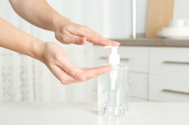 Kapalı mekanda antiseptik jel kullanan bir kadın.
