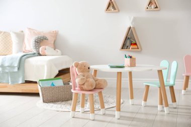 Küçük masa ve çocuk odasının içinde tavşan kulaklı sandalyeler.