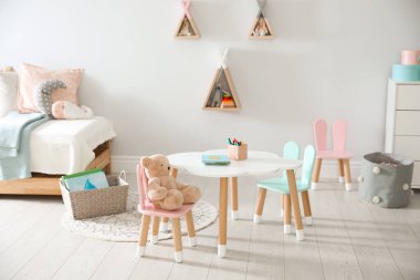 Küçük masa ve çocuk odasının içinde tavşan kulaklı sandalyeler.