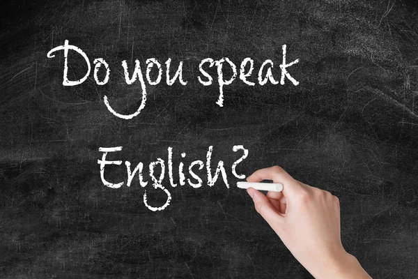 Woman writing question DO YOU SPEAK ENGLISH on blackboard, closeup