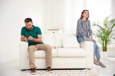 Young man preferring smartphone over his girlfriend at home. Relationship problems clipart