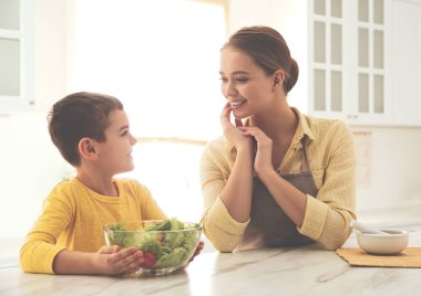 Anne ve oğlu mutfakta salata pişiriyor.