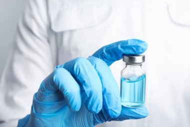 Doktorun elinde ilaç şişesi var, yakın plan. Aşılama ve aşılama