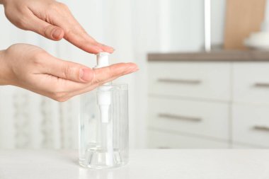 Kapalı alanda antiseptik jel kullanan bir kadın, yakın plan. Metin için boşluk