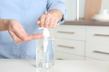Kapalı alanda antiseptik jel kullanan bir kadın, yakın plan. Metin için boşluk