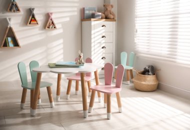 Küçük masa ve çocuk odasının içinde tavşan kulaklı sandalyeler.