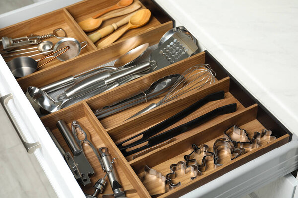 Different utensils in open desk drawer indoors, closeup