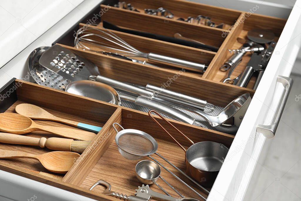 Different utensils in open desk drawer indoors, closeup