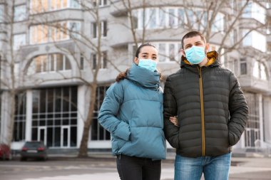 Dışarıda tek kullanımlık maskeler takan bir çift. Tehlikeli bir virüs.