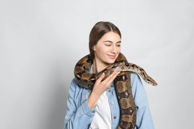 Arka planda boa yılanı olan genç bir kadın. Egzotik hayvan