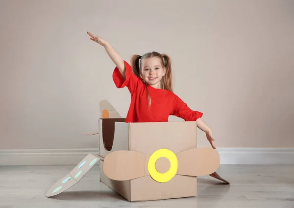 Cute Little Child Playing Cardboard Plane Beige Wall — Stock fotografie