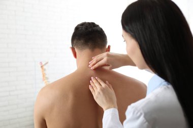 Profesyonel ortopedist, muayenehanedeki adamı muayene ediyor.