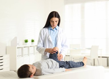 Klinikte küçük bir hastanın bacağını muayene eden profesyonel ortopedist.