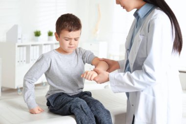 Klinikte küçük bir hastanın kolunu muayene eden profesyonel bir ortopedist.